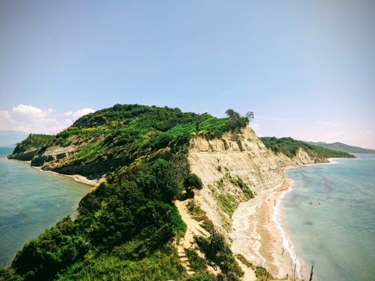 Green headland and pale cliffs at Cape of Rodon extend into the Adriatic Sea under a clear sky