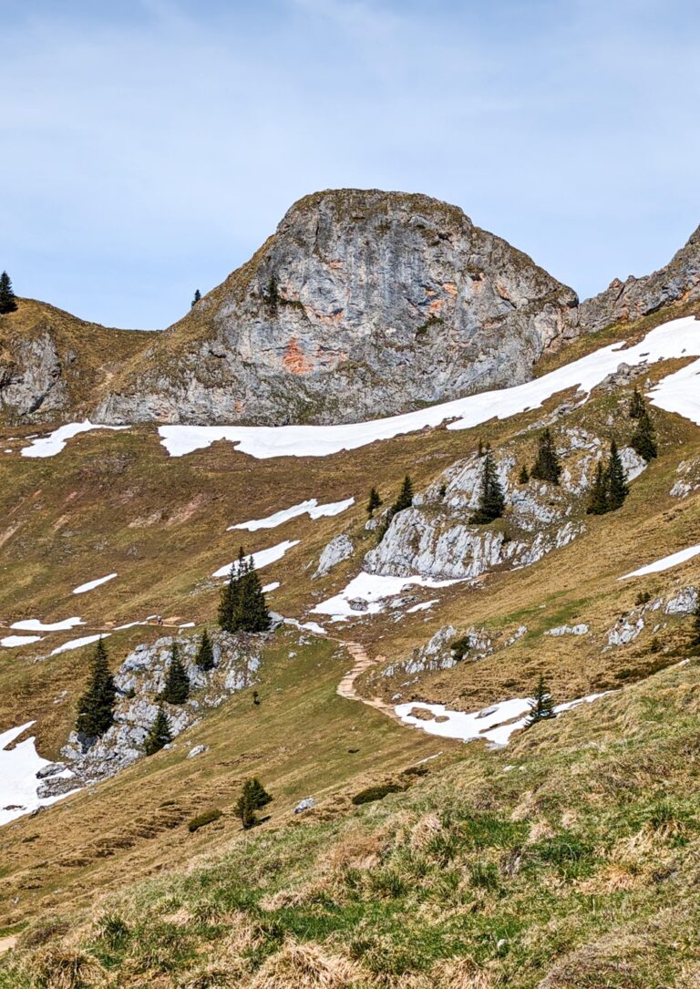 Rocky Rotwand peak above a winding trail, with lingering snow patches on the alpine slope