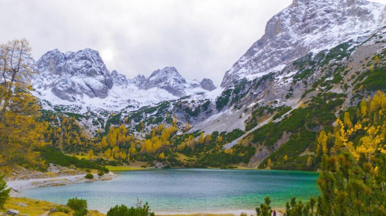 Seebensee beneath snow dusted alpine peaks, with yellow autumn trees along the shore