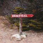 Red hiking trail sign in quiet forest path, inviting adventure and exploration.