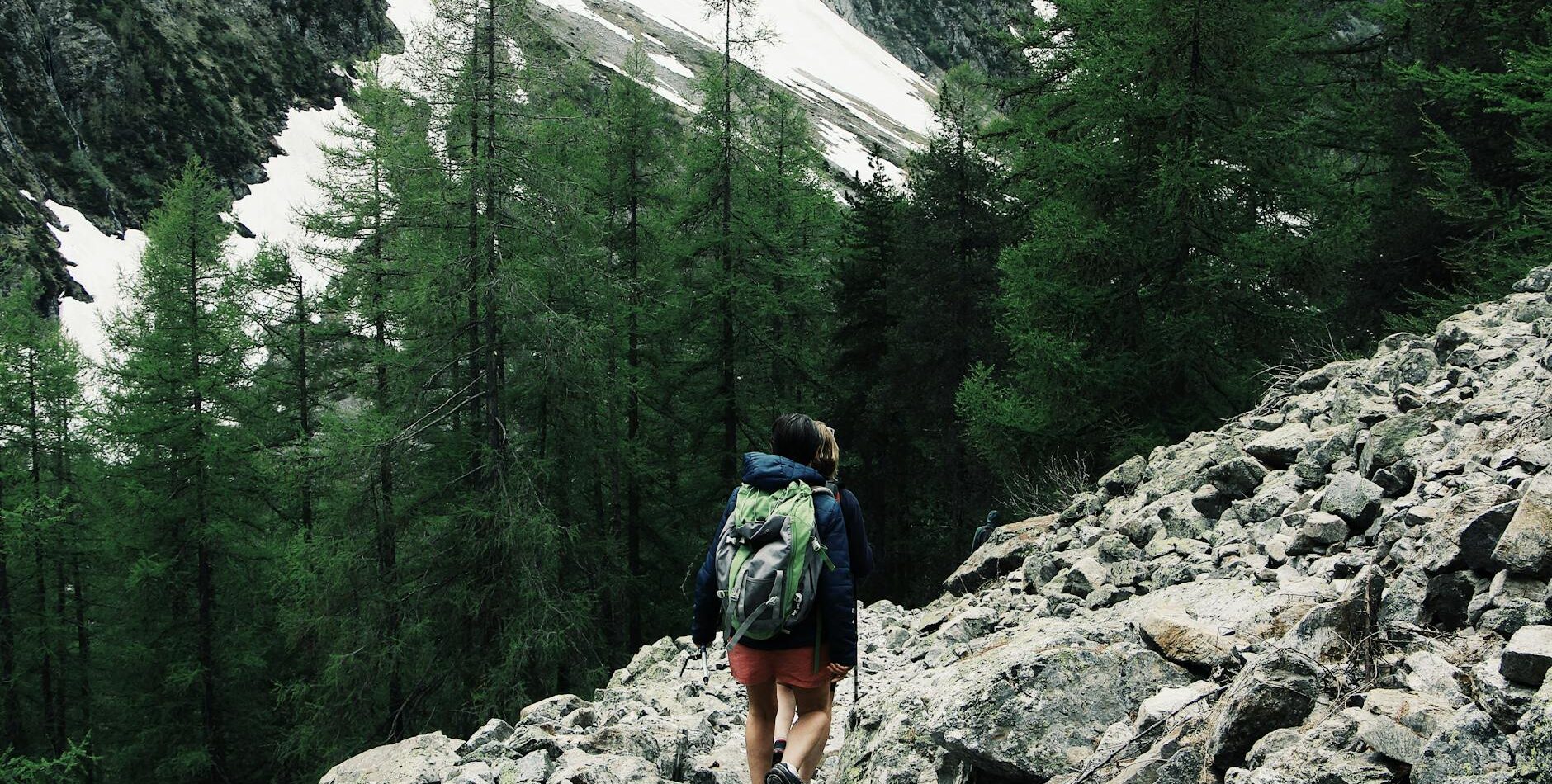 A backpacker hiking through rocky terrain in Champoléon, France with snowy peaks.
