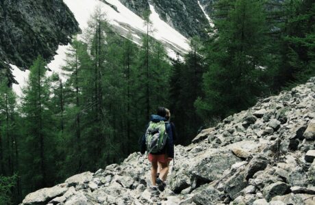 A backpacker hiking through rocky terrain in Champoléon, France with snowy peaks.