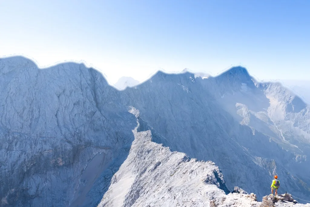 A climber on the grey limestone ridge of the Alpspitze