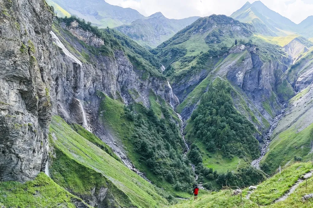 The Batöni waterfall arena: a green valley below waterfalls and peaks