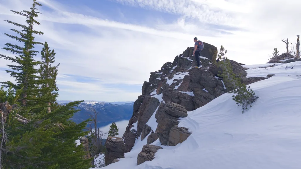 A hiker on a snowy granite top on the way to Rifle Peak